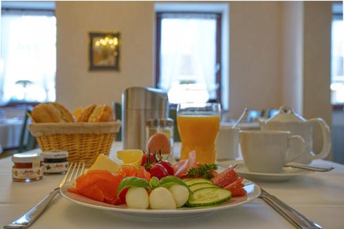 a plate of fruit and vegetables on a table with a drink at Hotel Kischers Landhaus in Hannover
