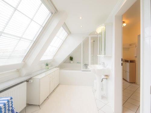 a white bathroom with a skylight and a sink at Haus Regina in Timmendorfer Strand