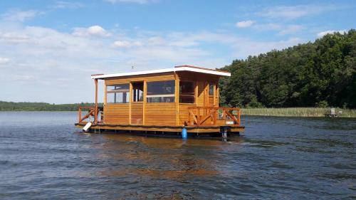 a tiny house on a dock in the water at Hausboot / Floss in Canow