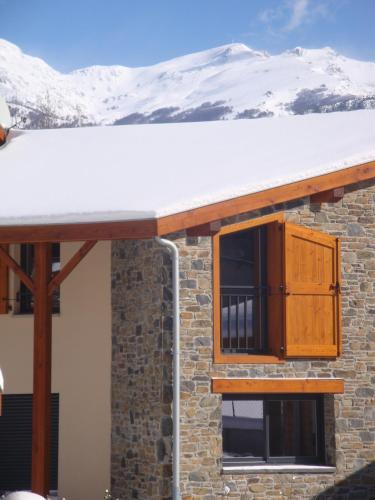a snow covered roof on a house with a snow covered mountain at Les Granges de Leo in Aston