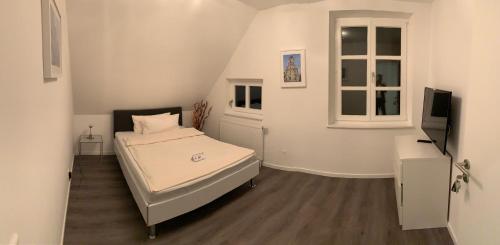 a small white bedroom with a bed and a window at Zentrum Appartment Neuburg in Neuburg an der Donau