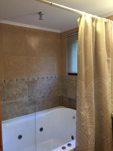 a bath tub with a shower curtain in a bathroom at Encanto del Rio in Villa La Angostura