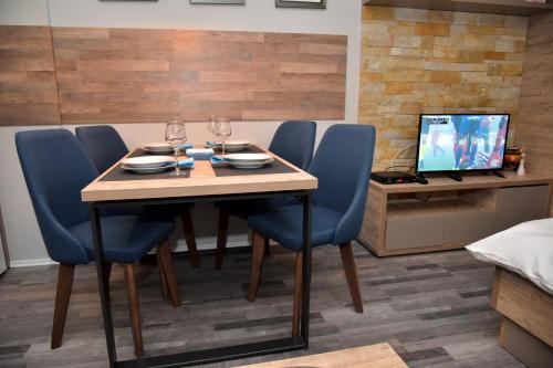 a dining room table with blue chairs and a television at Apartman Sladjana Premier 12 Milmari in Kopaonik