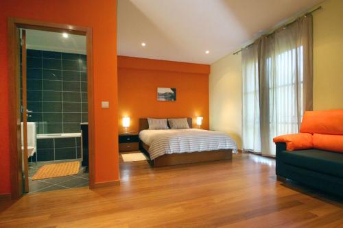 1 dormitorio con paredes de color naranja, 1 cama y 1 sofá en Encostas da Torre, en Terras de Bouro