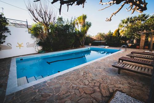a swimming pool with a bench next to a house at Villa Soula in Anavissos