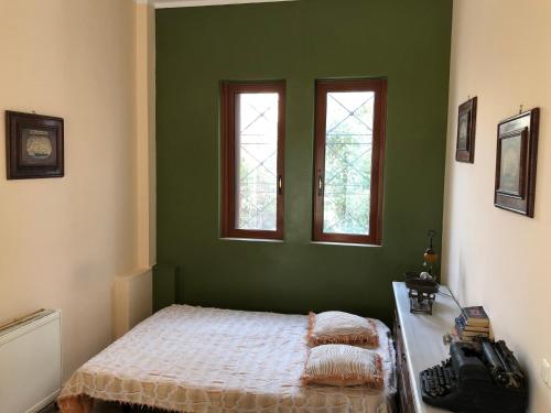 a green bedroom with a bed and two windows at Villa Soula in Anavissos