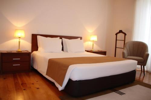 a bedroom with a bed with two lamps and a chair at Guest house Santa Maria in Funchal