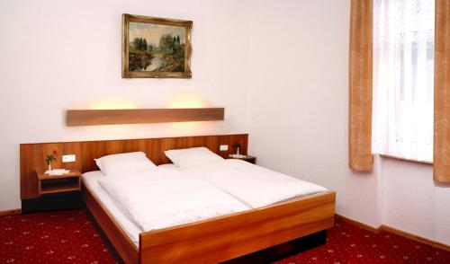 a bedroom with a large bed with white sheets at Hotel Café Post in Rüdesheim am Rhein