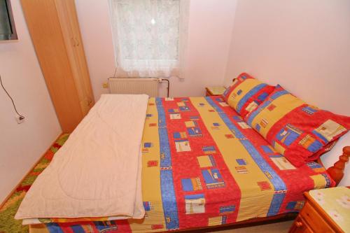 a bed with a colorful comforter in a bedroom at Vila As in Zlatibor