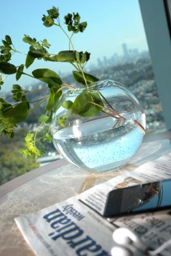 a glass vase sitting on a table with a plant in it at Hotel Associa Shin-Yokohama in Yokohama