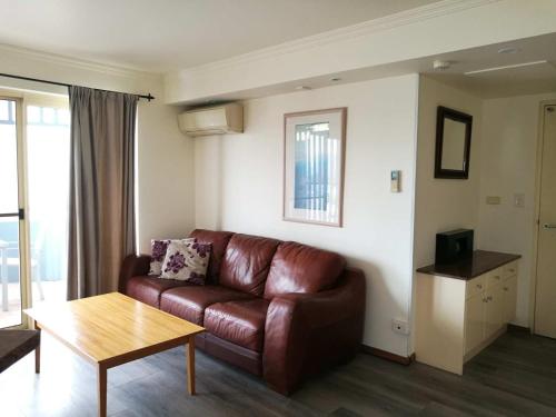 a living room with a brown leather couch and a table at The Sedgebrook On Leichhardt in Brisbane