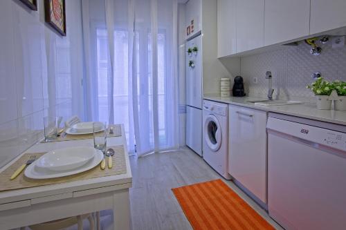 a kitchen with a sink and a washing machine at Carla Apartamentos in Nazaré