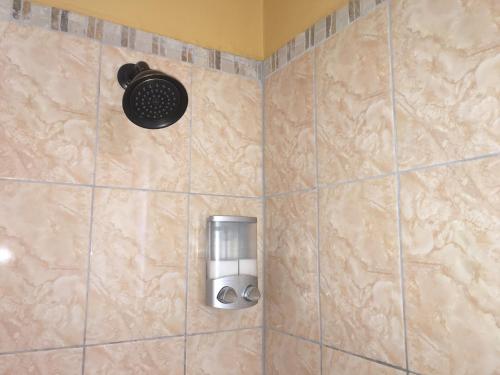 a shower with a soap dispenser on a tiled wall at Castle by the Shore in Ocho Rios