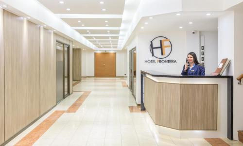 a woman standing at a reception desk in a lobby at Hotel Frontera Clásico in Temuco