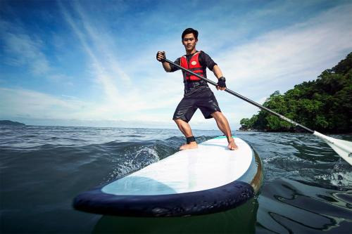 a man riding a paddle board on top of a body of water at Shangri-La Rasa Ria, Kota Kinabalu in Kota Kinabalu