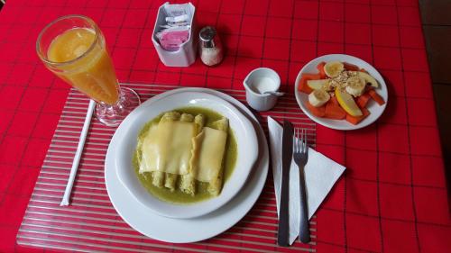 a red table with a plate of food and a glass of orange juice at Hotel Posada San Jerónimo in Coatepec