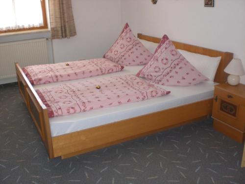 una cama con almohadas rosas en una habitación en Ferienwohnungen Winter, en Lohberg