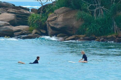 two women sitting on surfboards in the water at ANB Surf View in Tangalle