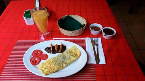a red table with a plate of food and a drink at Hotel Posada San Jerónimo in Coatepec