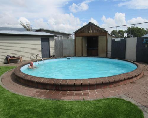 a woman swimming in a large pool in a yard at Palmerston North Motel in Palmerston North