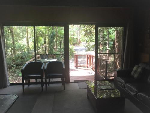 a living room with a table and chairs and a porch at Springbrook Mountain Chalets in Springbrook