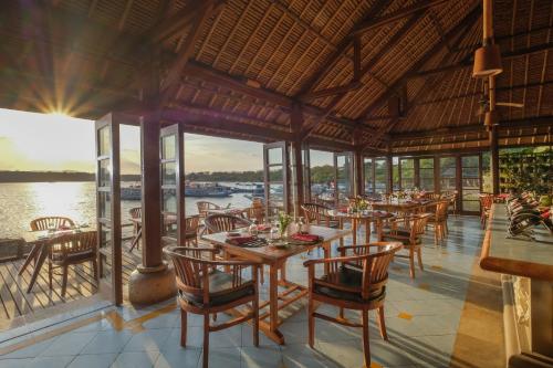 a restaurant with tables and chairs and a view of the water at Mimpi Resort Menjangan in Banyuwedang