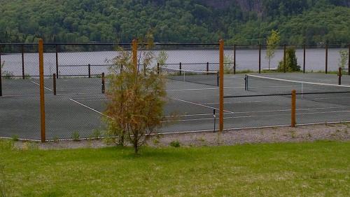 a couple of tennis courts next to a lake at Chalet F116 Mont-Tremblant Nord in Lac-Superieur
