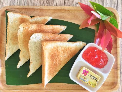 a plate with two slices of bread and a container of jam at Mango House in Sukhothai