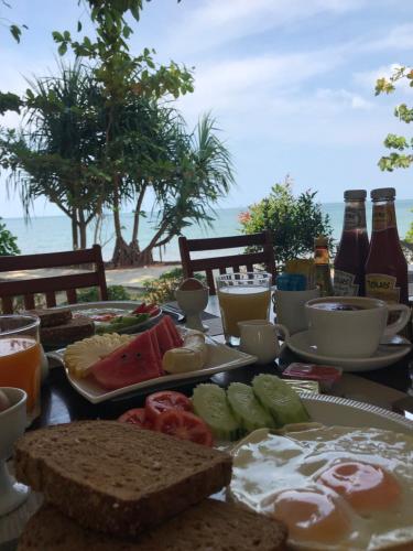 a breakfast table with eggs and bread and bottles of beer at Mupa Resort in Ko Jum
