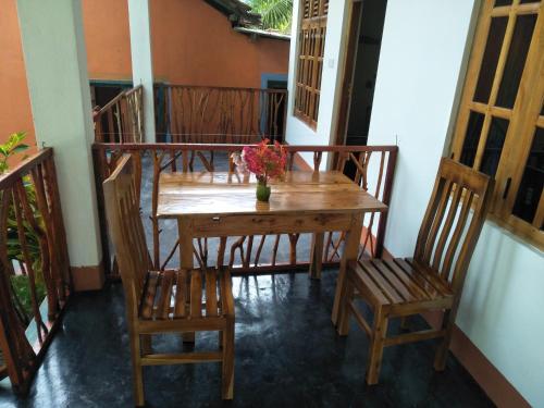 a wooden table with chairs and a vase of flowers on a balcony at Drift in Arugam Bay