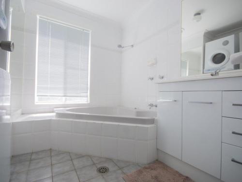 a white bathroom with a tub and a sink at Twin Peaks 1 in Blueys Beach