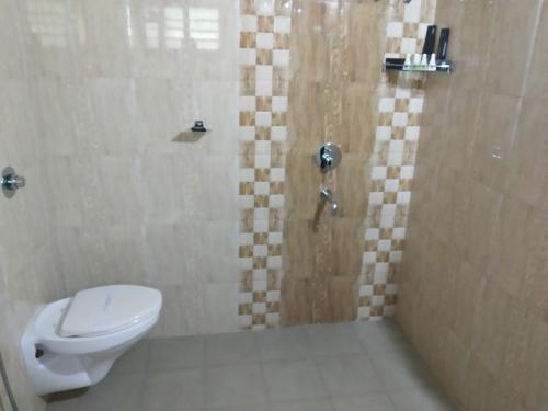 a bathroom with a toilet and a shower at Shoolin Resorts in Manipal