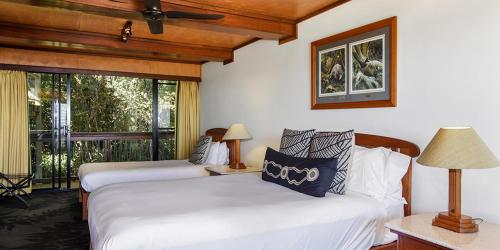 a bedroom with two beds and a balcony with a view at O'Reilly's Rainforest Retreat in Canungra