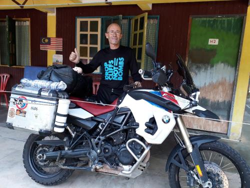 a man giving a thumbs up next to a motorcycle at Tahan Guest House in Kuala Tahan