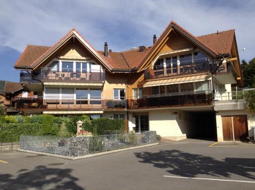 a large wooden house with a parking lot at Lake View Apartment in Faulensee