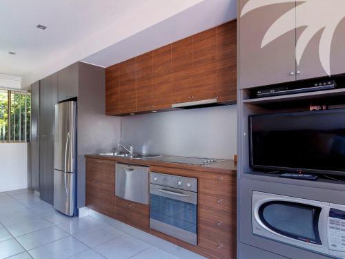 a kitchen with stainless steel appliances and wooden cabinets at Aqua Apartment 3 in Blueys Beach