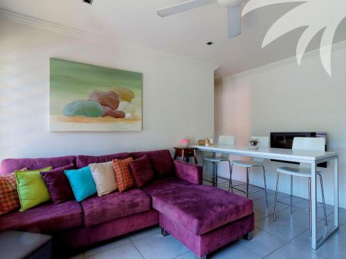 a living room with a purple couch and a table at Aqua Apartment 3 in Blueys Beach