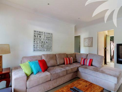 a living room with a brown couch with colorful pillows at Aqua Apartment 4 in Blueys Beach