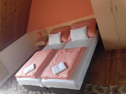 a bed with pink sheets and pillows in a room at Petra Vendégház in Bük