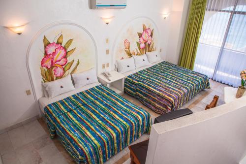 a bedroom with two beds and a mural of flowers at Hotel La Alondra in Barra de Navidad