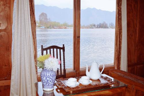 een tafel met vazen en een raam met uitzicht op het water bij Wangnoo Heritage Houseboats in Srinagar