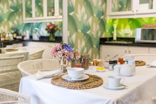 uma mesa com toalha de mesa branca e flores sobre ela em Lexden Guesthouse em Pietermaritzburg