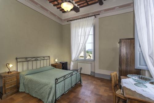 a bedroom with a bed and a table and a window at B&B Villa Pardi Lucca in Lucca