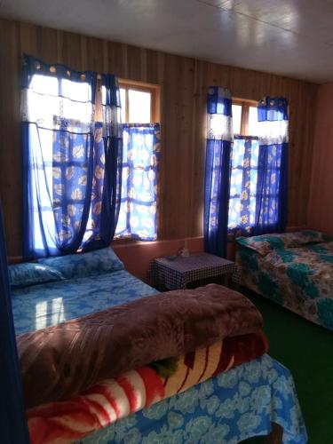 a room with two beds with blue curtains at Vamoose Anugraha in Mangpu