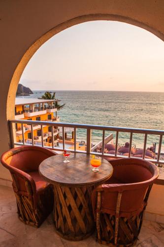 a table on a balcony with a view of the beach at Hotel La Alondra in Barra de Navidad