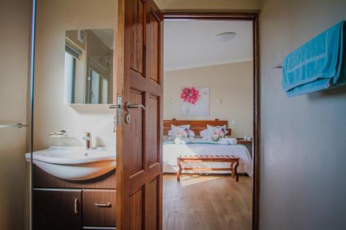 ein Bad mit einem Bett, einem Waschbecken und einer Tür in der Unterkunft Melk Houte Bosch Guest Farm in Swellendam