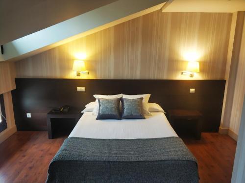 a bedroom with a large bed with two pillows at Hotel Puerta del Arco in Tudela de Duero