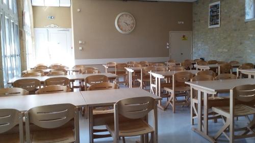 ein leeres Klassenzimmer mit Tischen und Stühlen und einer Uhr an der Wand in der Unterkunft Accueil du Couvent de Malet in Saint-Côme-dʼOlt