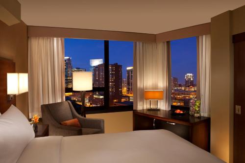ミネアポリスにあるミレニアム ミネアポリスのベッドルーム1室(ベッド1台付)、市街のスカイラインを望む窓が備わります。