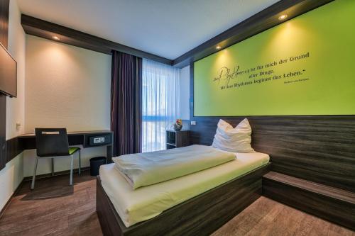 ein Schlafzimmer mit einem Bett und einer grünen Wand in der Unterkunft Economy-Hotel in Ulm